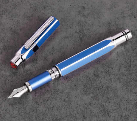 Blue and silver TWSBI Precision fountain pen on a dark gray surface