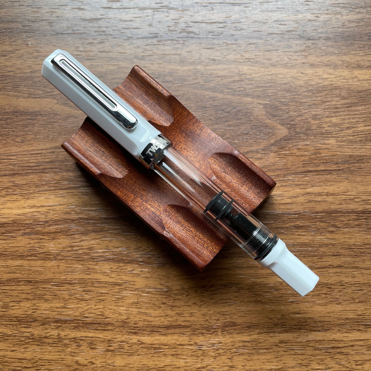 TWSBI ECO White Fountain pen with wooden holder on a wooden surface