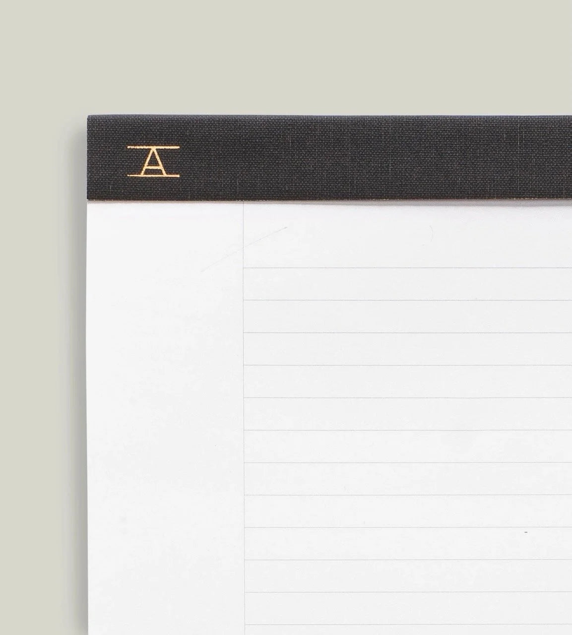 Closeup of Appointed Legal Pad bound with Charcoal Gray bookcloth and a gold foil Appointed logo in left corner, white paper with gray lined ruling.