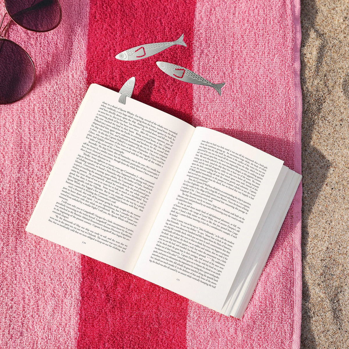 Fred and Friends Sardine Bookmarks in book on beach towel