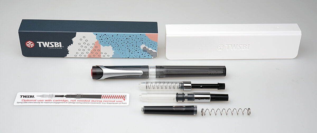 TWSBI Swipe Smoke fountain pen set laid out on a light gray background, including the pen, box, white case, and several pen components and accessories.