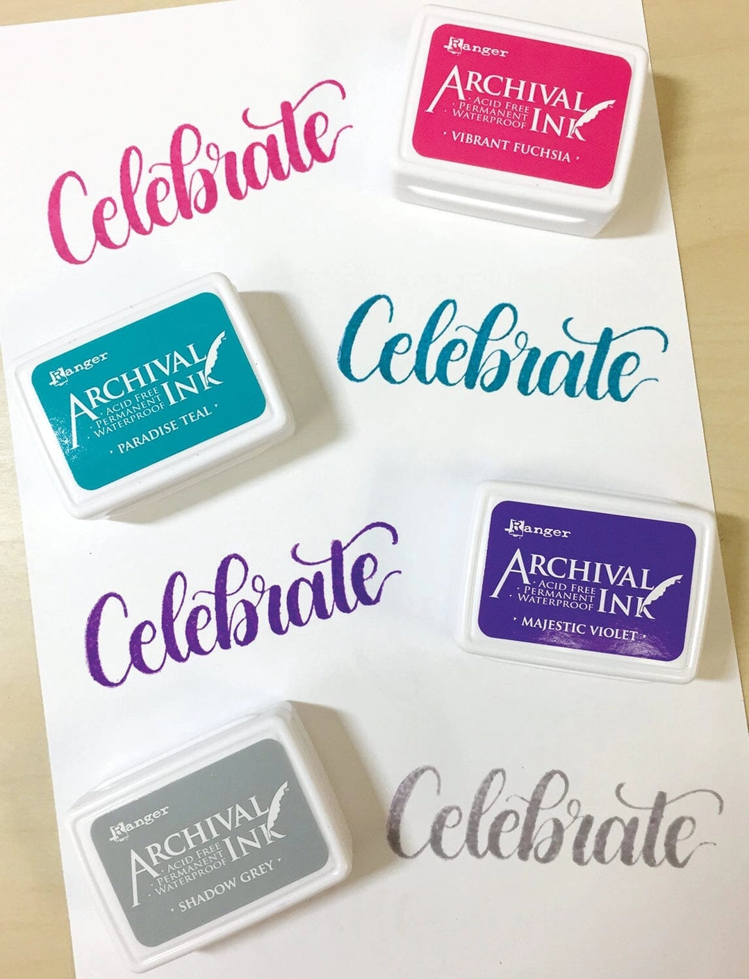 Ranger Ink Archival Mini Stamp Pads with Vibrant Fuschia, Paradise Teal, Majestic Violet and Shadow Grey inks Shown with Ink samples on white paper