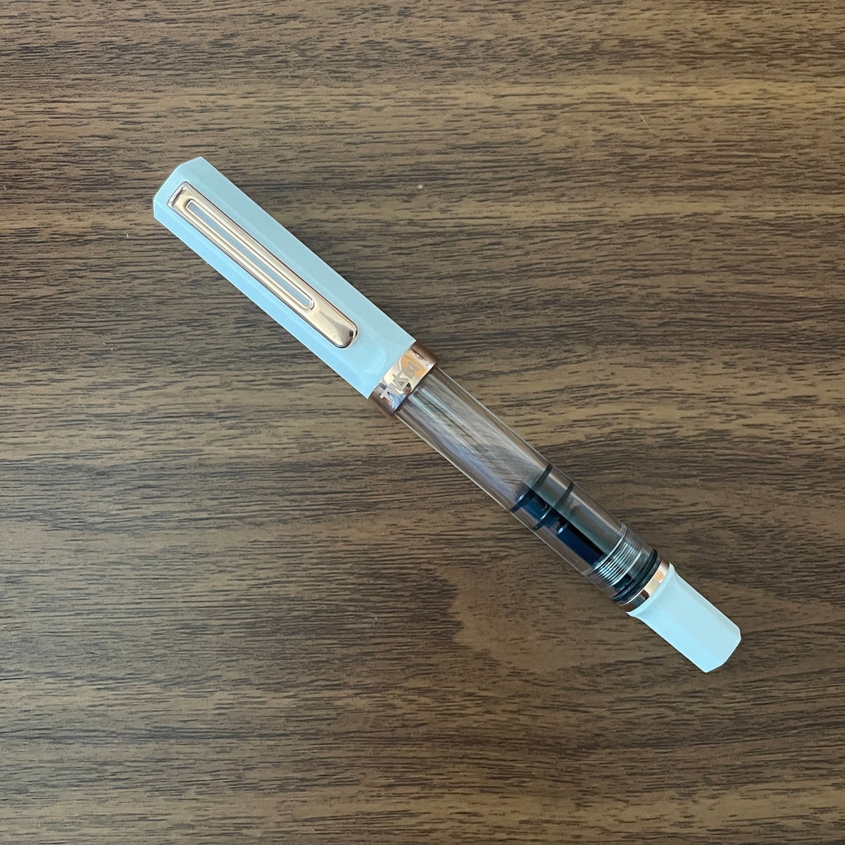 TWSBI White and Rose Gold Fountain pen capped on a wood table 