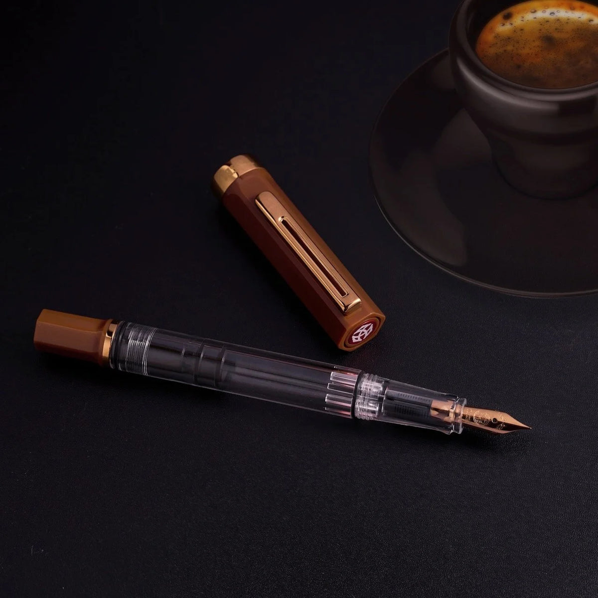 TWSBI Espresso Bronze Fountain pen on a dark surface with a cup of coffee in the background