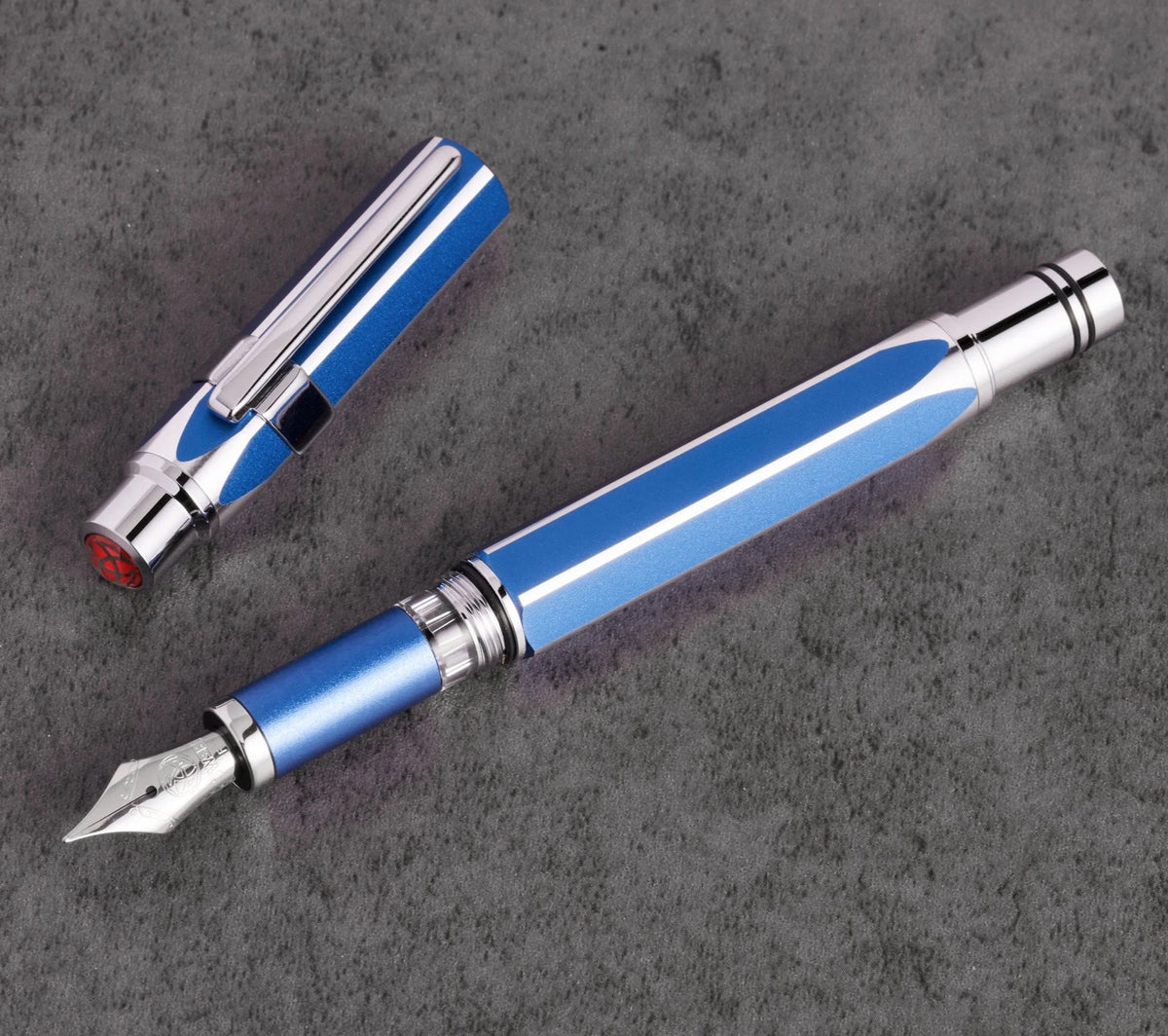 Blue and silver TWSBI Precision fountain pen on a dark gray surface