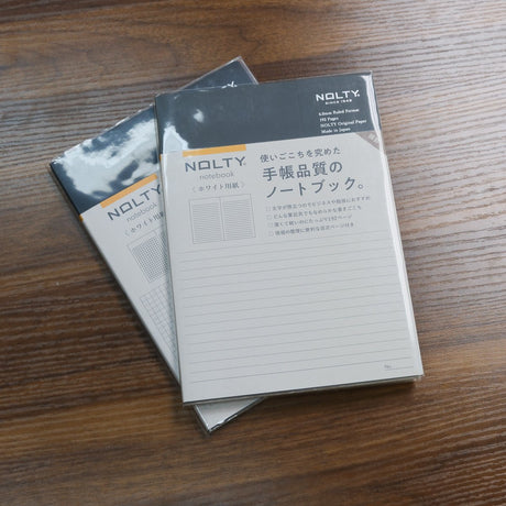 Two stacked NOLTY A5 Notebooks with black covers and 192 white pages, one lined and one grid.