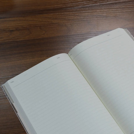 Closeup of top left corner of open NOLTY A5 Notebook with white lined pages and header for title and date.