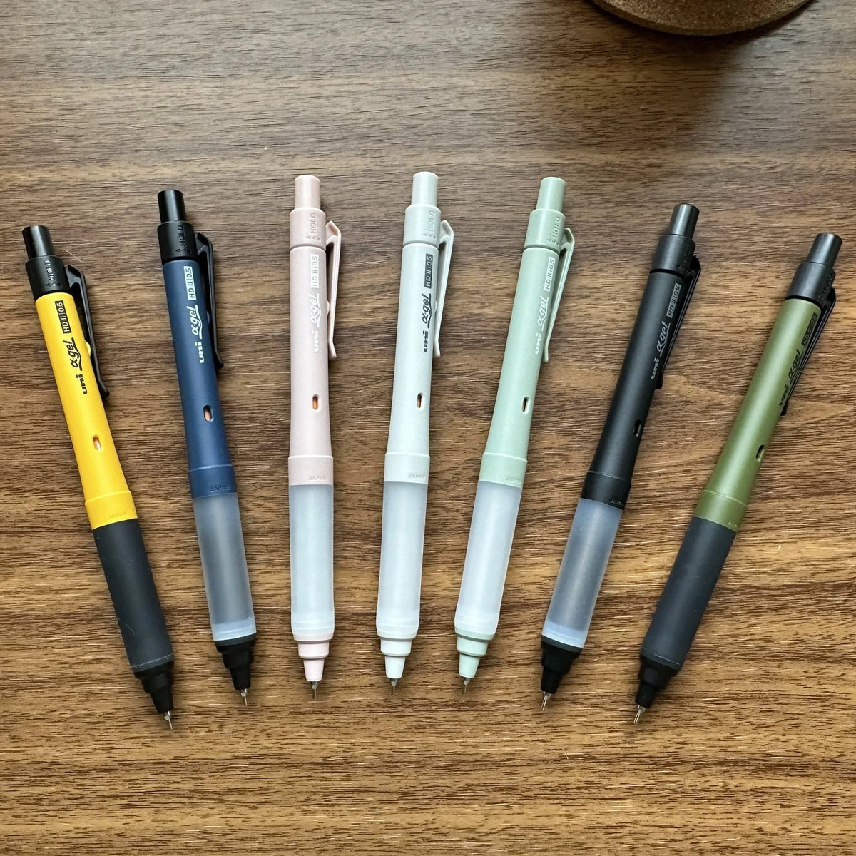 Seven Uni Kuru Toga Alpha Gel Switch mechanical pencils in different colors on a table.