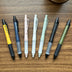 Seven Uni Kuru Toga Alpha Gel Switch mechanical pencils in different colors on a table.