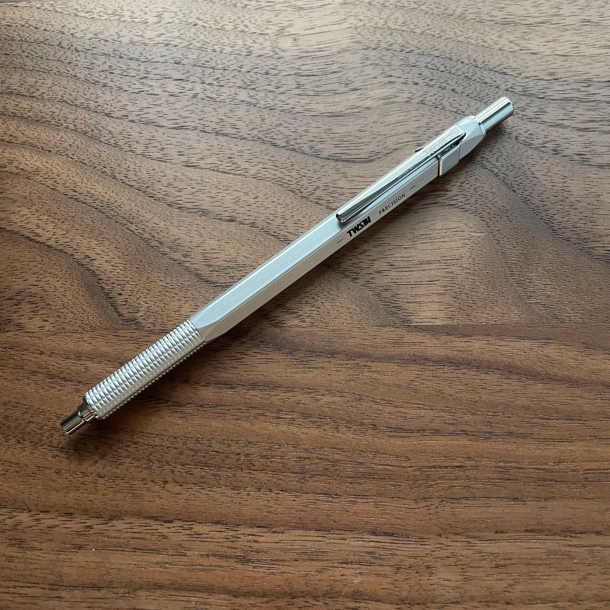 Silver TWSBI Precision Ballpoint Resting atop wood surface