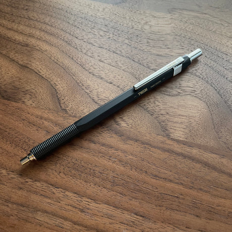 Black TWSBI Precision Ballpoint resting atop wood surface