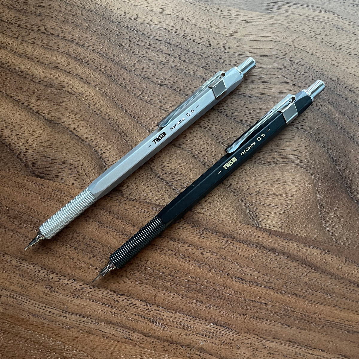 Two TWSBI Precision mechanical pencils on a wooden surface