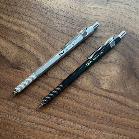 Two TWSBI Precision mechanical pencils on a wooden surface