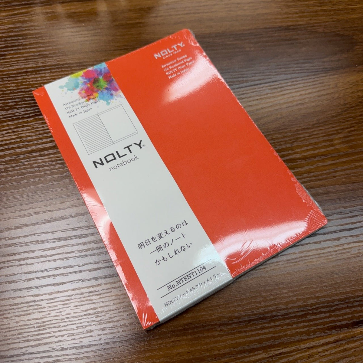 NOLTY A5 Notebook with orange cover and asymmetry (lined on left page, dot grid on right page) layout.