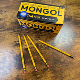Mongol #2 Woodcase pencils shown with a closed gross box and three woodcase pencils on a desk