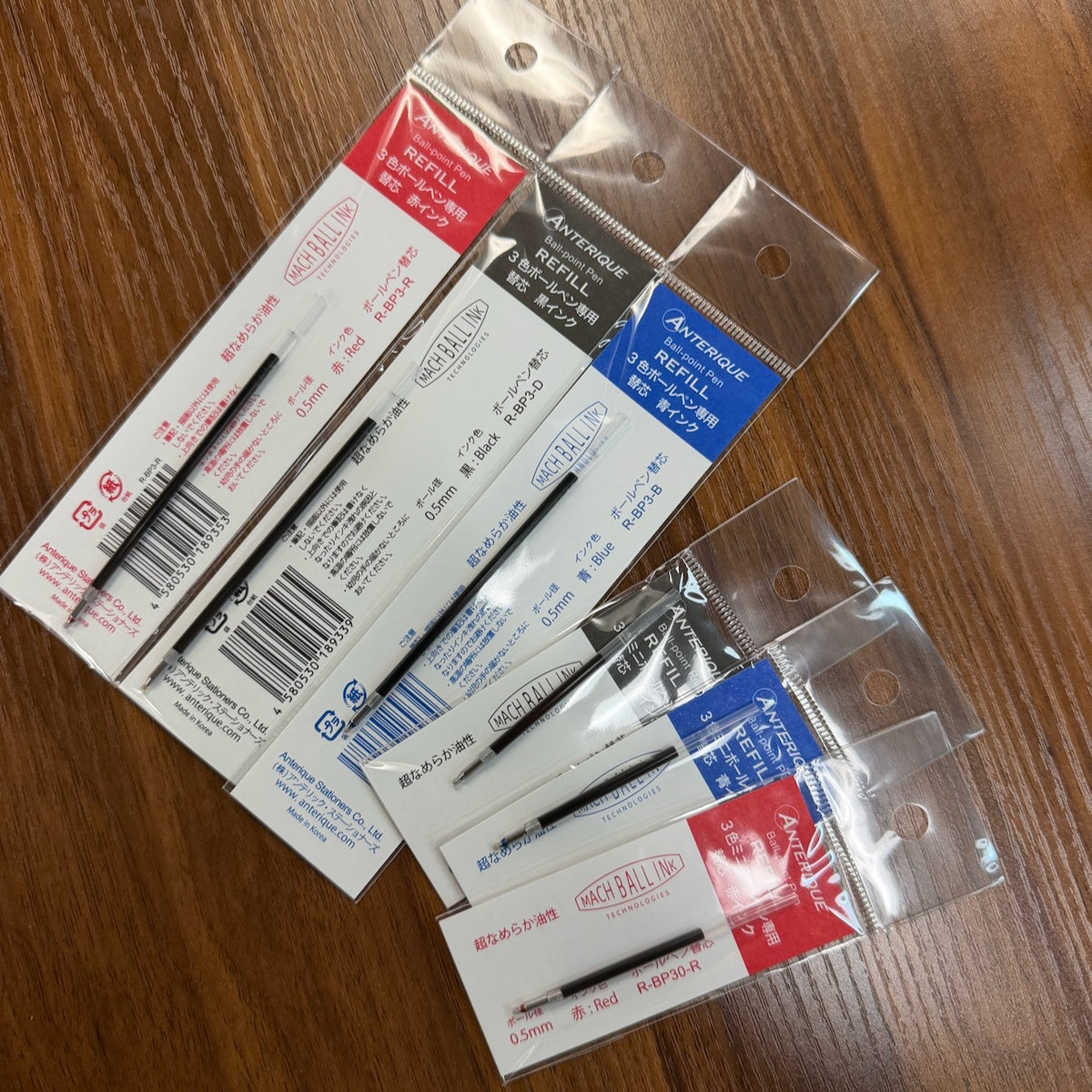 Anterique Three-Color Multi Pen Refills in Black, Blue, and Red and two different sizes, standard and mini, arranged on a table