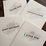 Four letterpress greeting cards with dark text and a flourish design on thick, off-white paper with messages Thank You, Congratulations, Happy Birthday!, and I Love You.