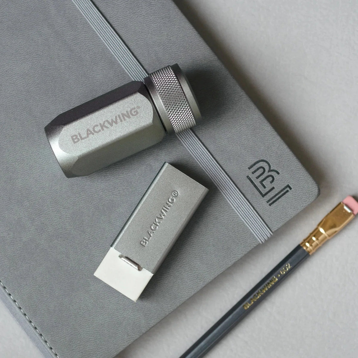 Blackwing Handheld Eraser Grey on table with sharpener and pencil