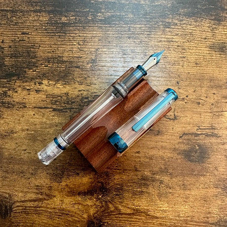 TWSBI Vac700R Kyanite Blue Resting Uncapped on a Wood Pen Stand. 
