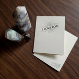 Letterpress greeting card with dark text 'I Love You' and flourish design on thick, off-white paper with Skylab Letterpress logo and artwork credit on back.