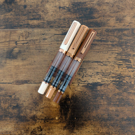 Three TWSBI Breakfast Collection pens in a transparent case on a wooden surface