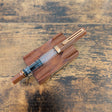 TWSBI Espresso Bronze fountain pen resting on a matching wooden pen stand over a rustic wood surface.