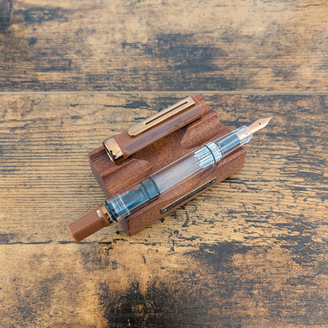 TWSBI Espresso Bronze Fountain pen with wooden case on a rustic wooden surface